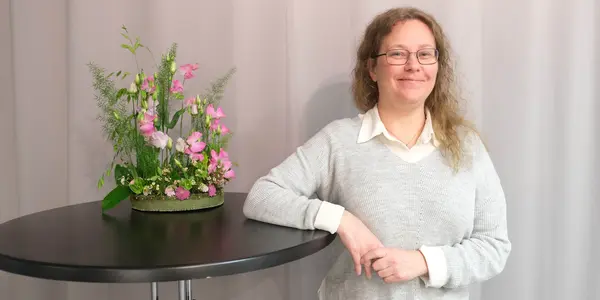 Kvinna som ler med blommor bredvid sig